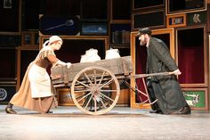 a man and woman standing next to a wooden wagon