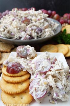 a plate with crackers, grapes and chicken salad on it