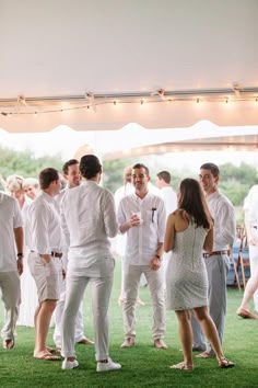 a group of people standing around each other in front of a tent with lights on it