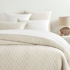 a bed with white quilts and pillows on it