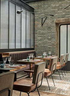 an empty restaurant with tables and chairs in front of a brick wall that has glass windows