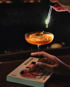 a person holding a cocktail in their hand with a straw sticking out of the top