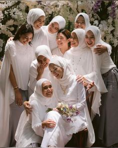 a group of women standing next to each other in front of a flower covered wall