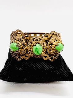 Beautiful Vintage Wide Art Deco Ornate Filigree Mottled Green Cabochon Bracelet. Lovely ornate holt filigree metal with embossed designs all the way around and applied filigree elements set with mottled green cabochons. Could use a polish but as always leave that up to buyer. Excellent vintage condition with age appropriate wear. Measures 1 1/2 inches wide in front and 1 inch wide in back. Opening is 2 1/2 inches across. Push in box clasp secure. Ornate Bronze Bracelets With Intricate Design, Formal Brass Bracelet With Intricate Design, Formal Brass Bracelets With Intricate Design, Ceremonial Green Bracelets With Intricate Design, Green Ceremonial Bracelets With Intricate Design, Antique Urn, Antique Jewelry, Vintage Antiques, Bangle Bracelets