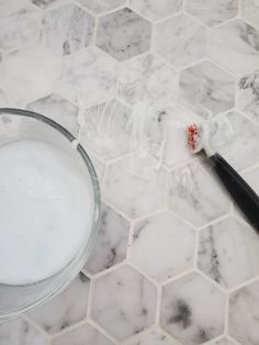 a toothbrush sitting on top of a marble counter next to a bowl of milk