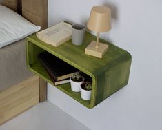 a green shelf with books and cups on it next to a lamp in a bedroom