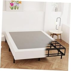 an image of a bed that is in the middle of some wood flooring and white walls