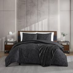 a bed with black comforter and pillows in a room next to a wall mounted plant