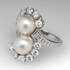 This captivating by-pass style ring is centered with two (2), post set, cultured saltwater pearls. The pearls are each bordered with six (6), prong set, round brilliant cut diamonds. The top face of the shank is accented with six (6), channel set, baguette cut diamonds on each side. The ring measures 24.1mm at the top, rises 10.0mm above the finger, tapering to 1.9mm wide and 1.6mm thick at the base of the shank. This ring is currently a size 6. The pearls in this ring appear to be from a strand Luxury Victorian Pearl Ring For Formal Events, Luxury Elegant Pearl Ring With Rose Cut Diamonds, Luxury Victorian Pearl Ring For Formal Occasions, Luxury Brilliant Cut Round Pearl Ring, Modern Luxury White Gold Pearl Ring, Pearl Rings Vintage Sales, Luxury Fine Jewelry Pearl Ring With Single Diamond, Luxury Oval Pearl Ring For Wedding, Luxury Unique Pearl Rings