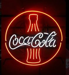 a neon coca cola sign hanging from the side of a building