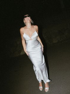 a woman standing in the dark wearing a white dress