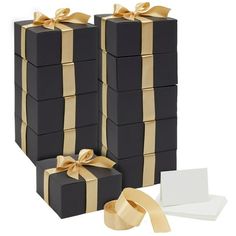 black and gold gift boxes with golden ribbon on each one, white card in the middle