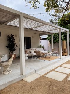 a covered patio with chairs and tables in the back yard, next to an outdoor living area