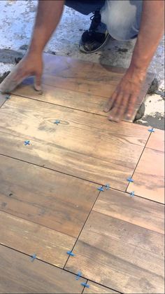 a man laying wood on top of a wooden floor with blue tape around the edges