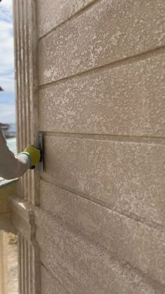 a man is holding onto the side of a building while using a screwdriver