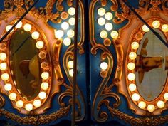 an ornately decorated blue and gold mirror with lights on it's sides is shown