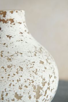 a white and brown vase sitting on top of a table