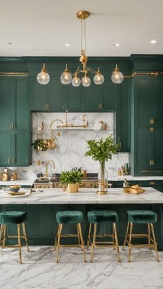 a large kitchen with green cabinets and marble counter tops, gold accents on the island