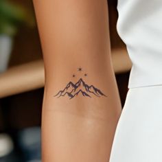 a woman's arm with a mountain tattoo on the left side of her body