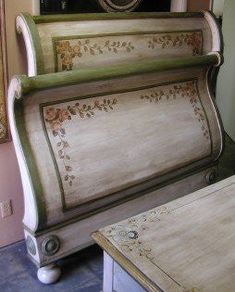 an old fashioned bed frame sitting on top of a wooden table next to a mirror