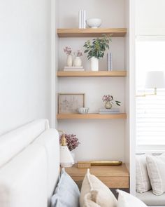 a living room filled with furniture and shelves next to a white couch in front of a window