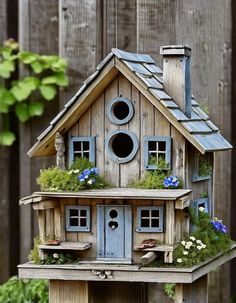 a bird house with plants and flowers on the roof