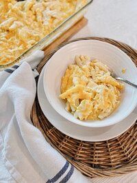 a white plate topped with macaroni and cheese next to a casserole dish