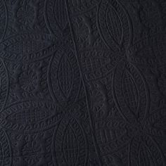 black quilted fabric with an intricate design on the front and back side, closeup