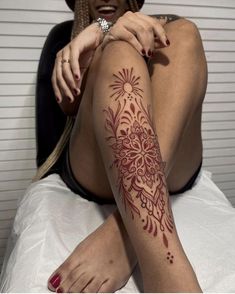 a woman sitting on top of a bed with tattoos on her arm and leg,