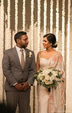 a man and woman standing next to each other in front of a wall with lights