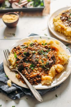 two white plates topped with mashed potatoes and meat