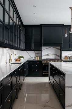 a kitchen with black cabinets and marble counter tops, gold accents on the handles and pulls