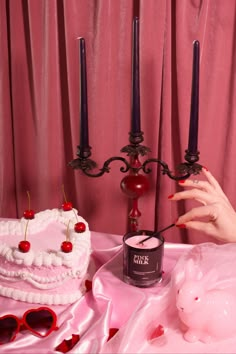 a pink table topped with a cake next to two candles and a pig figurine