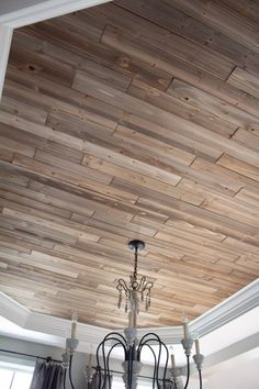 a chandelier hanging from the ceiling in a room with wood paneling on it