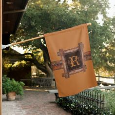 an orange banner hanging from a clothes line on a brick walkway in front of a house