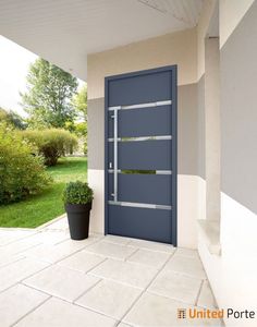 a blue door sitting on the side of a white wall next to a potted plant