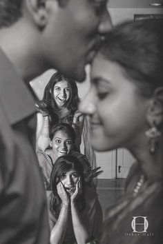 a man kissing a woman's cheek while she is surrounded by other people in black and white