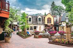 a cobblestone street with lots of houses and flowers in the center, surrounded by greenery