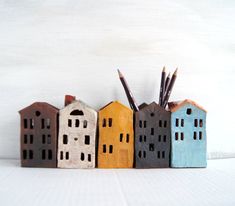 small wooden houses are lined up against a white background with pencils sticking out of them