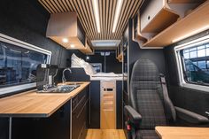 an interior view of a camper with wood flooring and black walls, including the kitchen