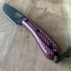 a red and black knife sitting on top of a wooden table