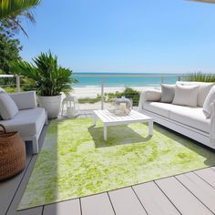 a living room filled with white furniture and green rugs on top of a wooden floor