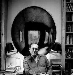 black and white photograph of a man sitting in front of a desk with books on it