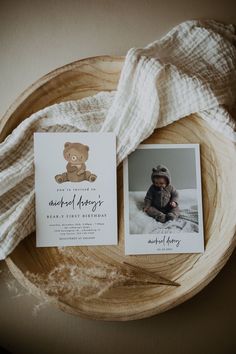 a teddy bear is sitting on top of a wooden plate next to a baby's birth announcement card