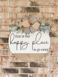 this is our happy place sign on the side of a brick wall with a bow