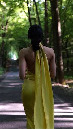 a woman in a yellow dress is walking down the road