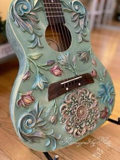 a green guitar sitting on top of a wooden table