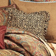 a leopard print pillow on top of a bed with an animal print comforter and matching pillows