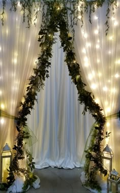 a wedding arch decorated with greenery and lights