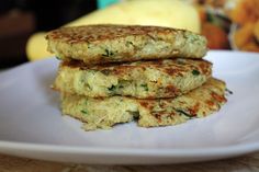 two crab cakes stacked on top of each other on a white plate with bananas in the background